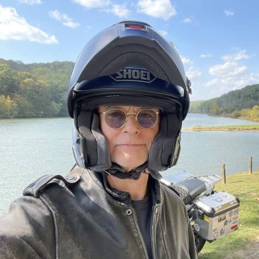 Sam Booth, BMW Riders Association Board of Trustee, with lake and mountain scene behind him